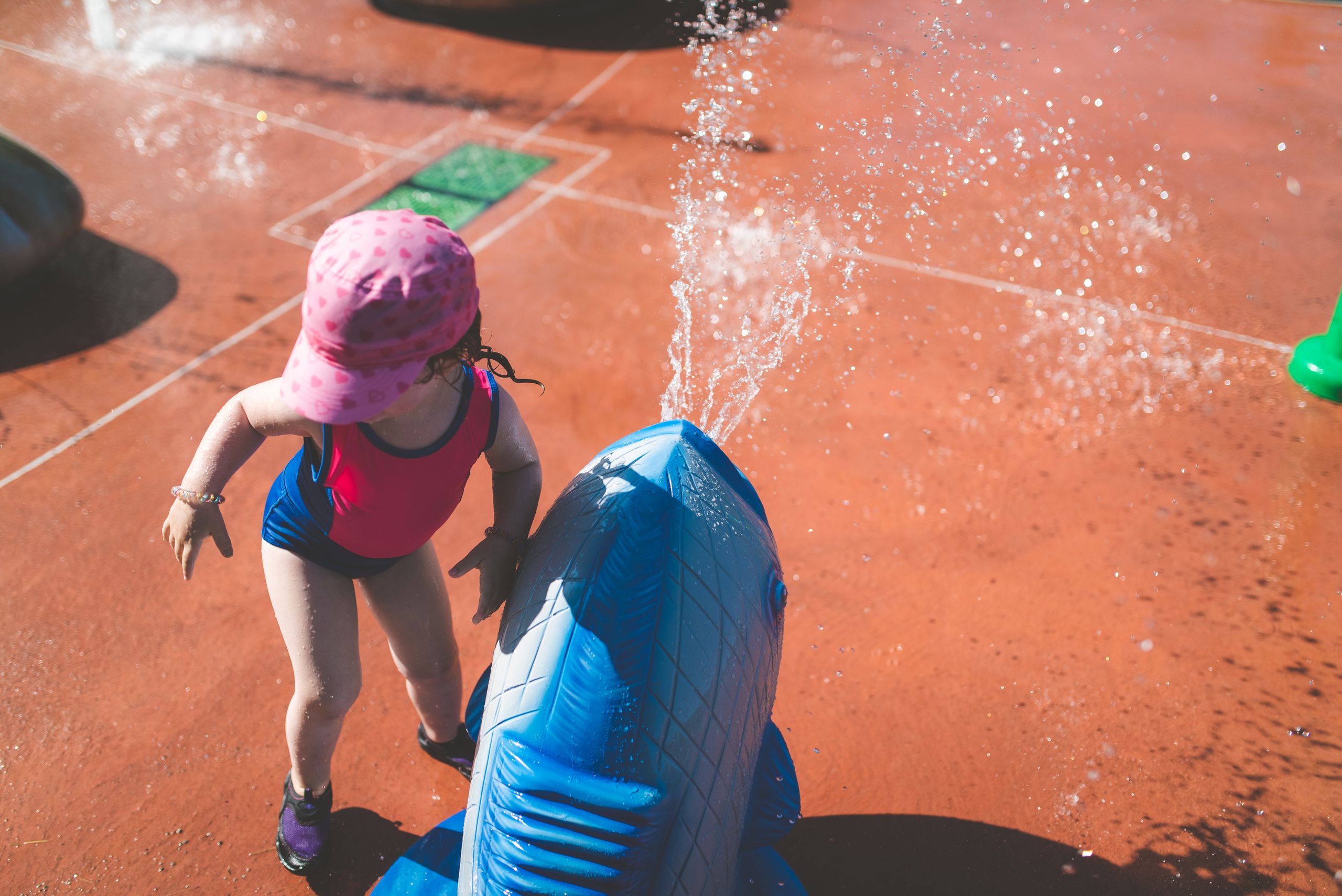 A young girl enjoys playtime at a water park, splashing with a colorful fountain.